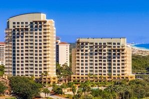 A high-rise hotel with multiple floors, balconies, and a view of the beach. - Cozy coastal condo with shared pool/hot tub and easy Bbach access (Miramar Beach)