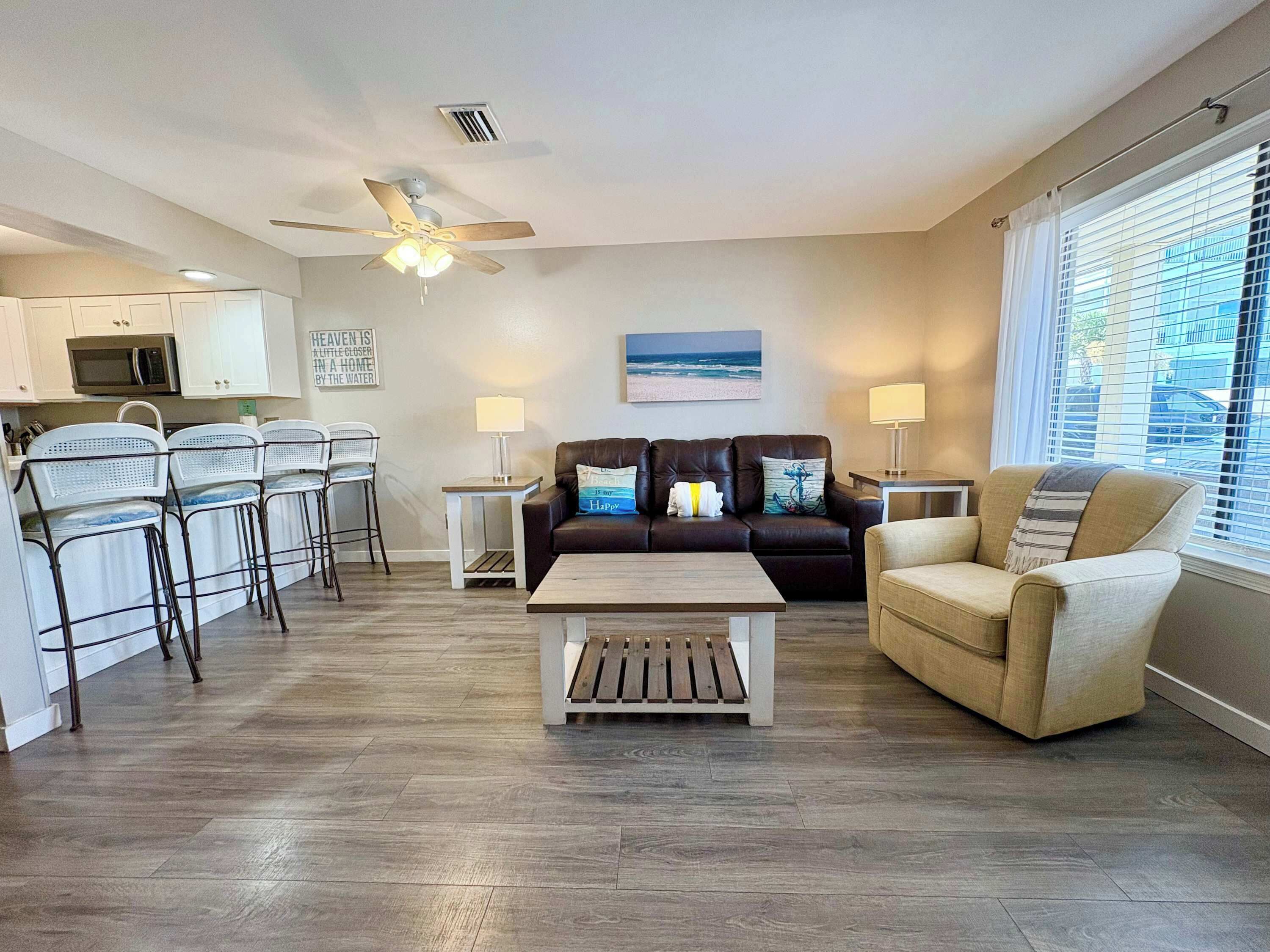 A modern living room with a sofa, chairs, a coffee table, and a ceiling fan.