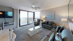 Ein Hotelzimmer mit Balkon, Fernseher, Sofa, Couchtisch und Lampe.
