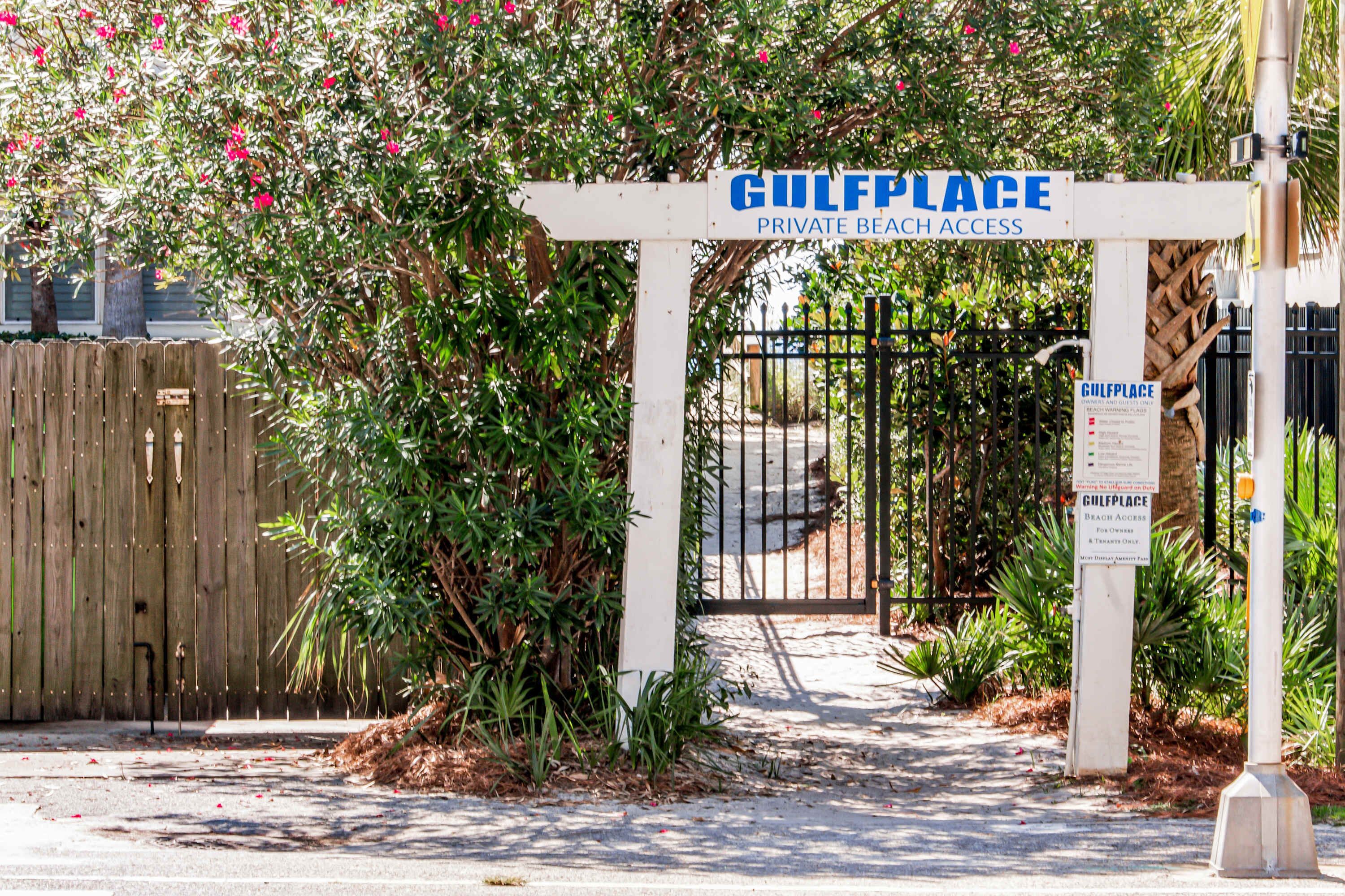A gated entrance to Gulfplace with a wooden fence and lush greenery.