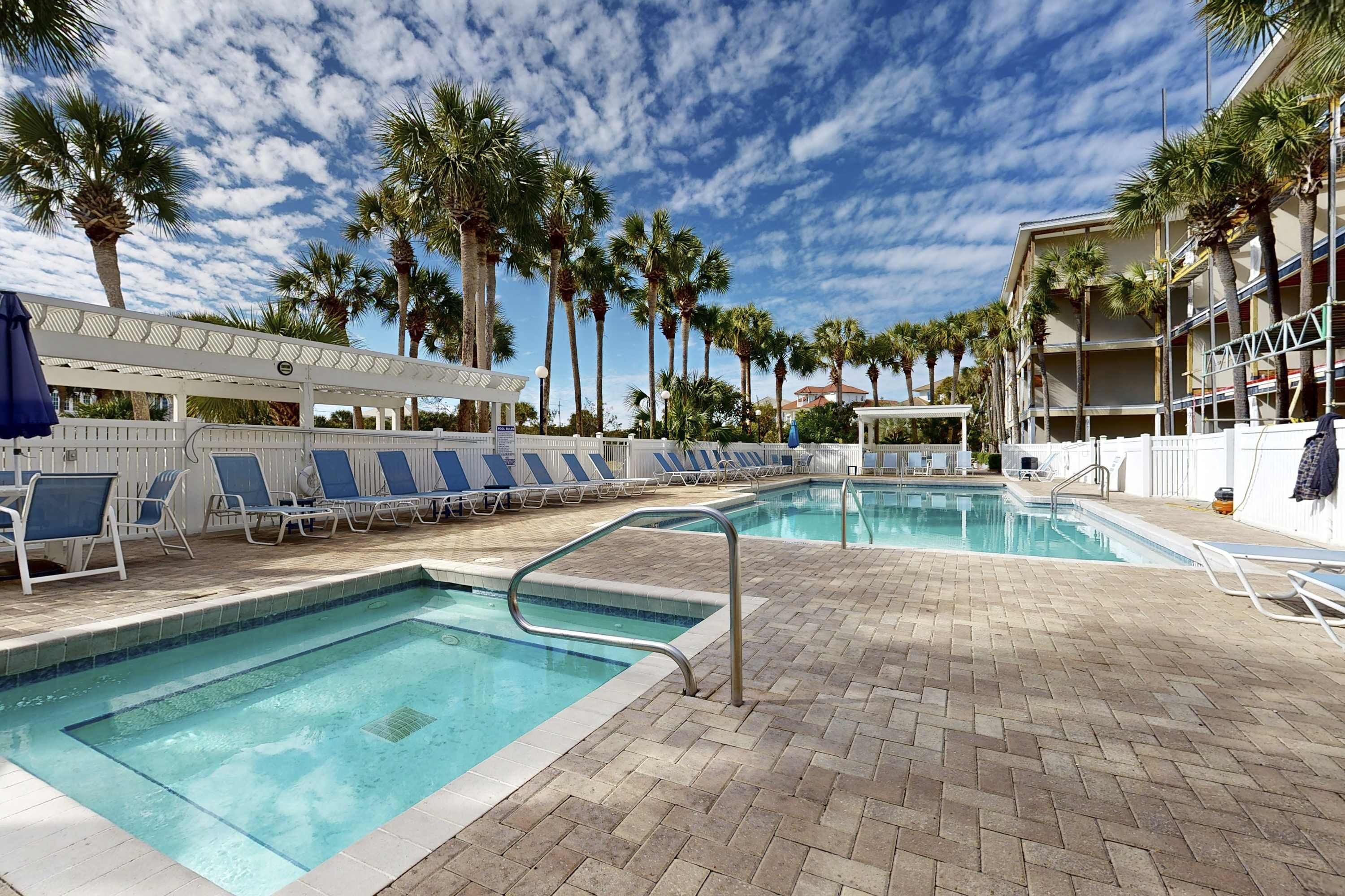 A pool area with lounge chairs and palm trees.