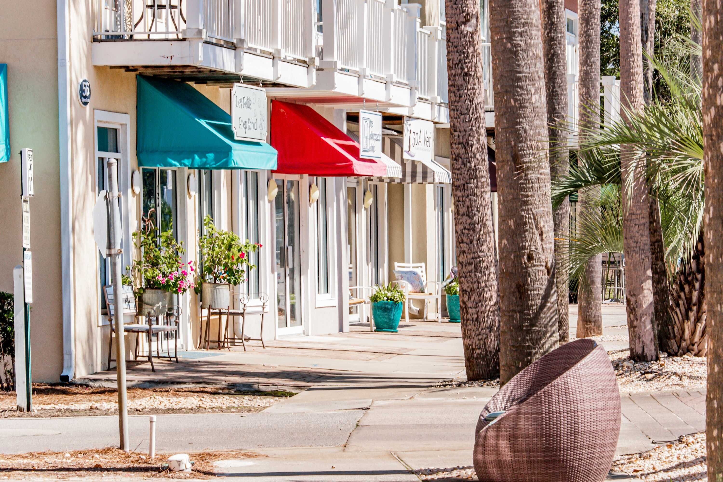 A row of beachfront hotels with outdoor seating and palm trees.