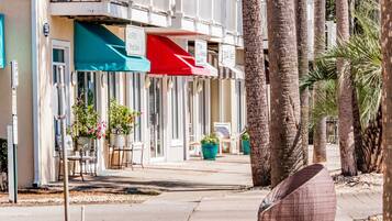 A row of beachfront hotels with outdoor seating and palm trees.