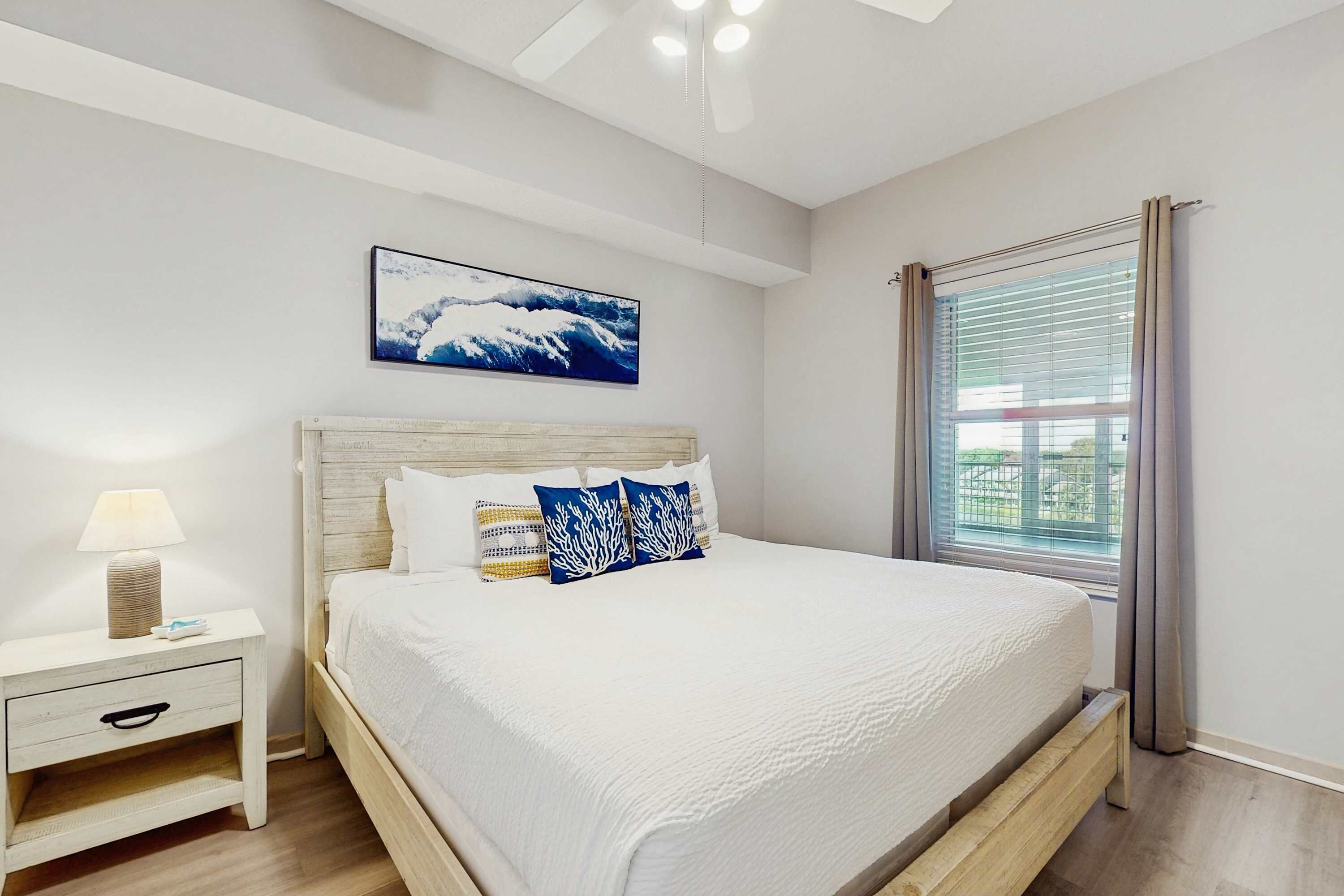 A bedroom with a bed, nightstand, and a window with curtains.