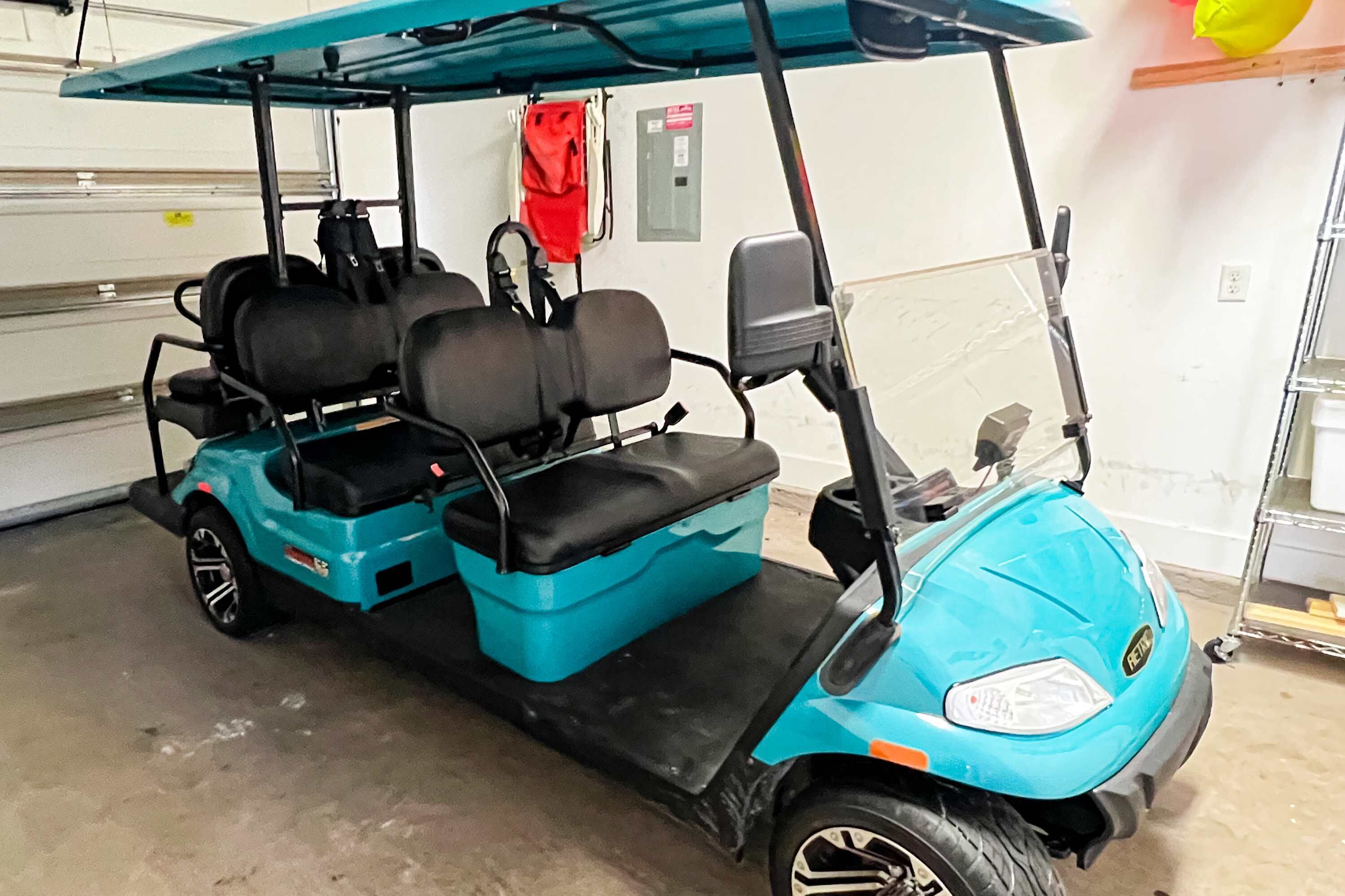 Ein blauer Golfwagen mit Verdeck, zwei Sitzen und Lenkrad.