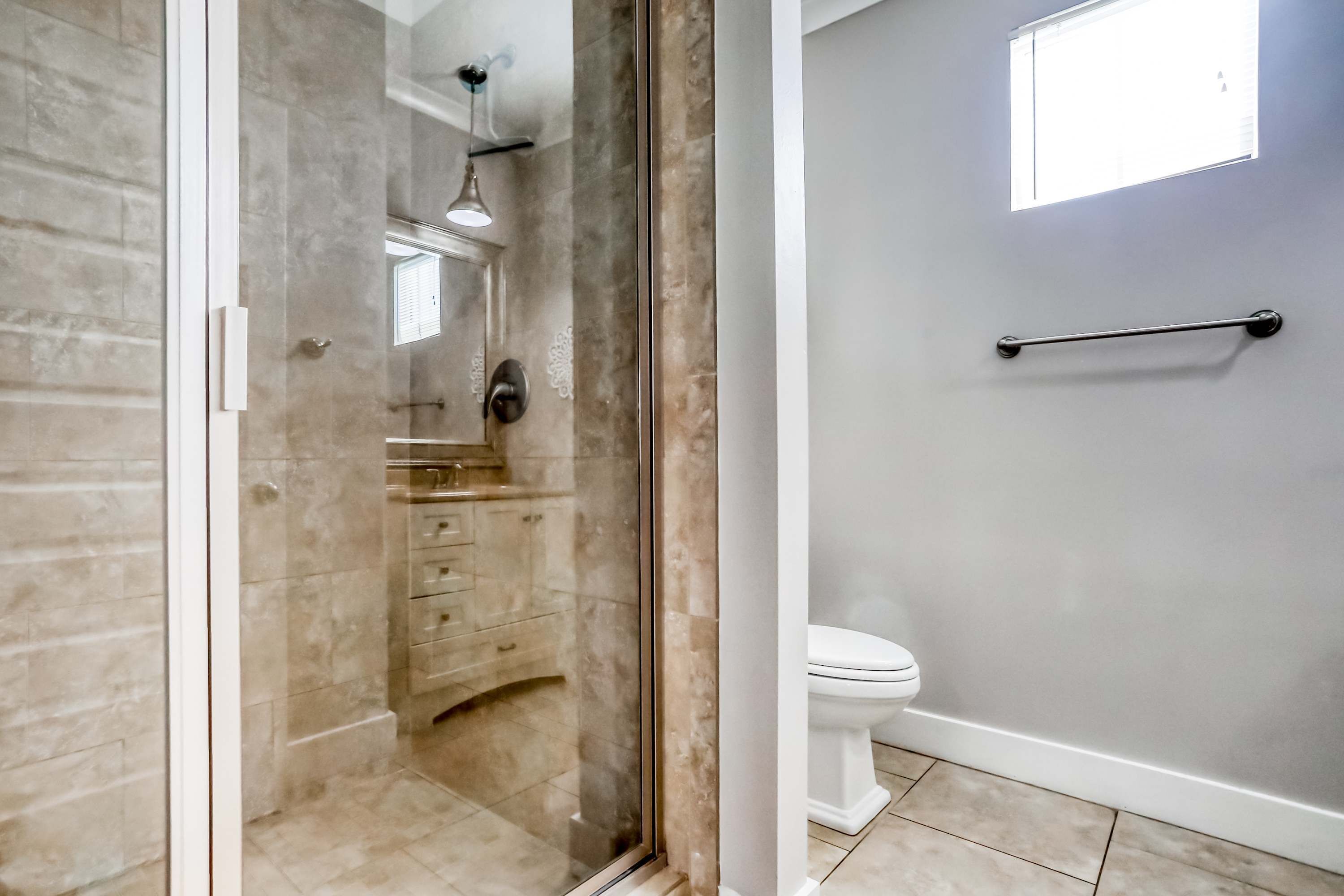 Baño con cabina de ducha de vidrio, inodoro y perchero para toallas.