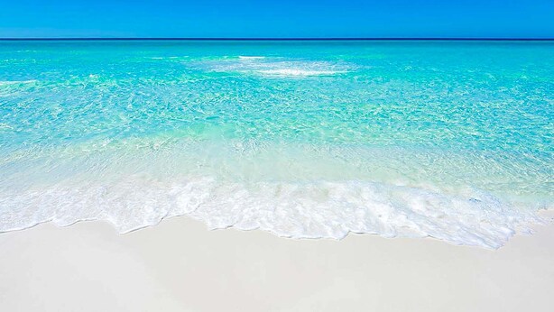 Una playa con aguas turquesas cristalinas y arena blanca.