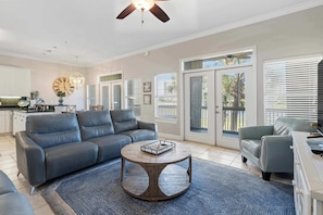 A living room with a gray sofa, a round coffee table, and a ceiling fan. - Lakefront condo with pool, pickleball, golf & private beach access (Miramar Beach)