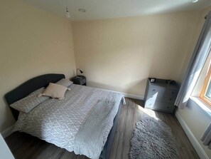 A bedroom with a bed, bedside tables, a dresser, and a window.