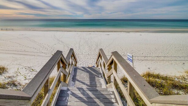 Eine Holztreppe führt zu einem Strand mit freiem Blick auf das Meer.