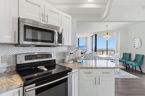 A modern kitchen with stainless steel appliances, a herringbone tile backsplash, and a view to the outside. - Waterfront getaway with ocean views, central AC & washer/dryer - walk to beach (Miramar Beach)