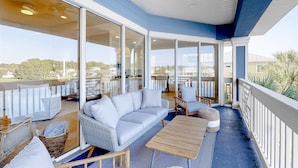 A spacious balcony with a white sofa, wooden table, and wicker chairs. - Lakefront condo with water-view balcony, private golf cart, resort pool & amenities (Miramar Beach)