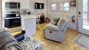 A cozy cabin interior with a kitchenette, a sofa, a television, and a fireplace. - Caney Creek | Great Views, Large Deck (Cosby)