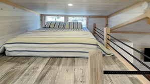 A cozy attic bedroom with a wooden bunk bed, a striped bedspread, and a view through a window. - Caney Creek | Great Views, Large Deck (Cosby)