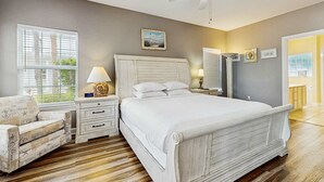 A bedroom with a large bed, a nightstand, a chair, and a ceiling fan. - Bright townhome with patio, fenced yard & pool - near shops and dining (Miramar Beach)