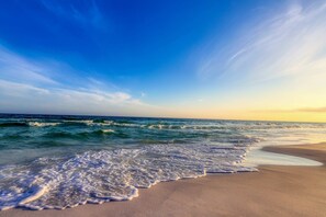 Uma praia com ondas suaves beijando a costa sob um céu claro.