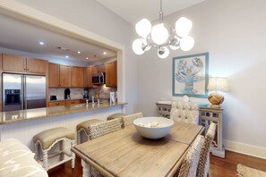 Une cuisine moderne avec des meubles en bois, des appareils en acier inoxydable et un coin repas comprenant une table en bois et des chaises en osier.