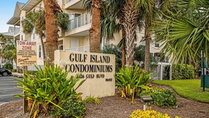 Señal de Condominios Gulf Island con aviso de zona de remolque.