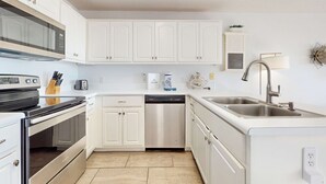 Una cocina moderna con armarios blancos, electrodomésticos de acero inoxidable y lavavajillas integrado.