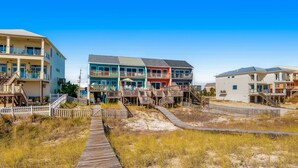 Una propiedad frente al mar con un paseo marítimo de madera que conduce a edificios coloridos de varios pisos y balcones.