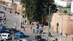 Une rue animée en milieu urbain, avec des voitures, des piétons et un bâtiment historique en arrière-plan.