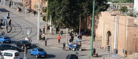 A busy urban street with cars, pedestrians, and a historic building in the background.