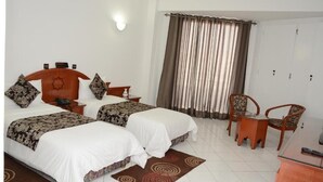 Une chambre d’hôtel avec deux lits, un bureau, une chaise et une armoire.