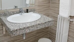 Une salle de bain avec un lavabo sur un plan de travail en granit, un miroir et des carreaux beiges à rayures.