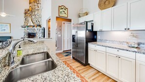 A modern kitchen with granite countertops, stainless steel appliances, and white cabinetry. - Gorgeous condo with ocean views, inviting balcony, bright interior, washer/dryer (Santa Rosa Beach)