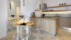 A modern kitchen with a central island, clear chairs, and a dining table. - Naousa Story 1 ❤ (Paros)
