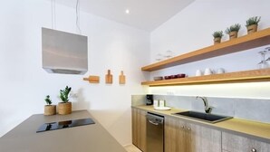 A modern kitchen with a built-in dishwasher, wooden cabinets, and a countertop with potted plants. - Naousa Story 1 ❤ (Paros)