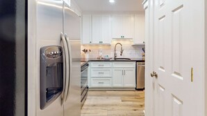 A kitchen with white cabinets, a stainless steel refrigerator, and a sink. - Bright Townhouse with High-Speed WiFi, Private Washer&Dryer, and Pool (Santa Rosa Beach)