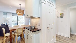 A modern kitchen with white cabinetry, a dining table with chairs, and a hanging light fixture. - Bright Townhouse with High-Speed WiFi, Private Washer&Dryer, and Pool (Santa Rosa Beach)