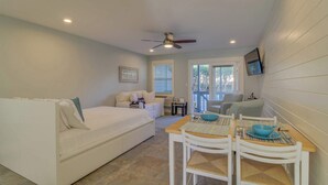 A compact living space with a bed, a dining table with chairs, and a ceiling fan. - Completely Remodeled Beachside Studio with Pool - Snowbirds Welcome (Inlet Beach)