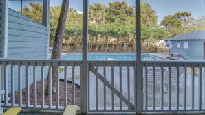A pool area with a wooden deck, a small house, and trees in the background. - Completely Remodeled Beachside Studio with Pool - Snowbirds Welcome (Inlet Beach)