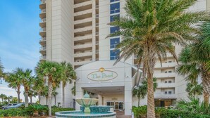 Ein Hotel Eingang mit einem Schild mit der Aufschrift "The Pearl", umgeben von Palmen und einem Brunnen.