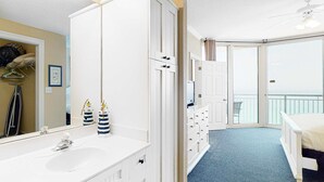 Ein Schlafzimmer mit einem großen weißen Schminktisch, einem Bett und einem Balkon mit Blick.