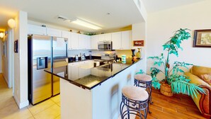 Una cocina moderna con armarios blancos, electrodomésticos de acero inoxidable y una isla central con taburetes.