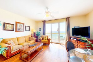 Un salón con sofá, sillón, mesa de centro, televisor y un balcón con vistas.