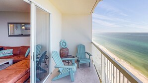 Un balcone con vista sull'oceano, un divano e due poltrone Adirondack.