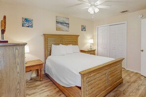 A bedroom with a wooden bed, a nightstand, a lamp, and a ceiling fan. - Beachy townhouse with 11 pools, golf, fast WiFi & private W/D (Panama City Beach)