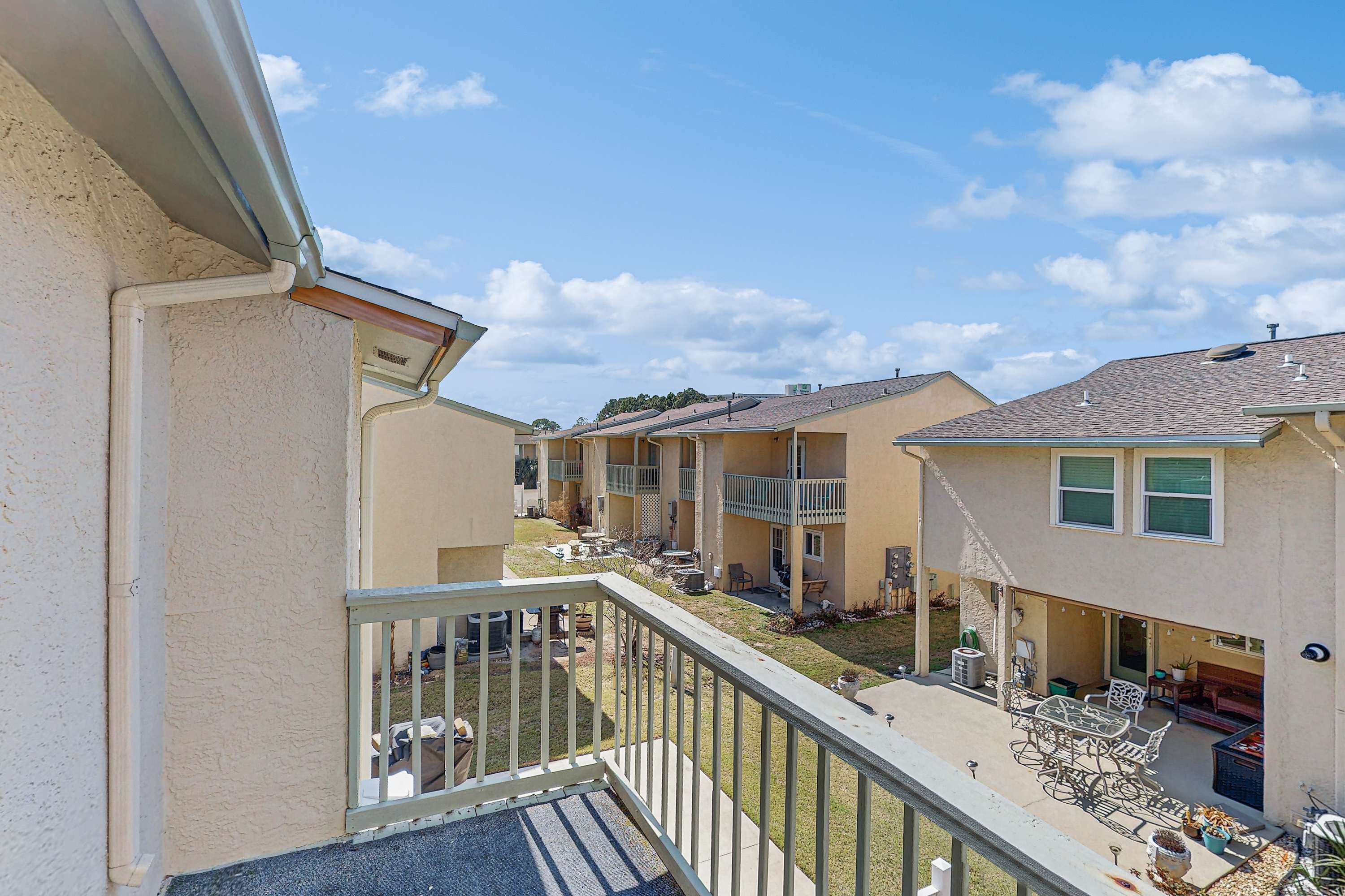 A residential building with multiple balconies, outdoor seating areas, and a clear sky.