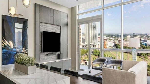 Una sala de estar moderna con un televisor grande, una zona de comedor y vistas a la ciudad.