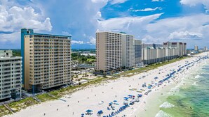 Ein Strandhotel mit mehreren Hochhäusern, einem Sandstrand und zahlreichen Sonnenschirmen.