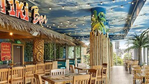 A restaurant with a tropical theme, featuring wooden furniture and a mural of a palm tree on the ceiling. - FIFA Luxury-1BR Presidential Ste-Parking Incl.-Walk to Stadium-Sleeps 4 (Atlanta)