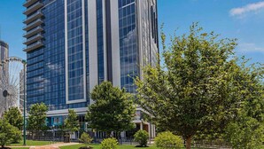 A modern building with a glass facade, surrounded by trees and a Ferris wheel in the background. - FIFA Luxury-1BR Presidential Ste-Parking Incl.-Walk to Stadium-Sleeps 4 (Atlanta)
