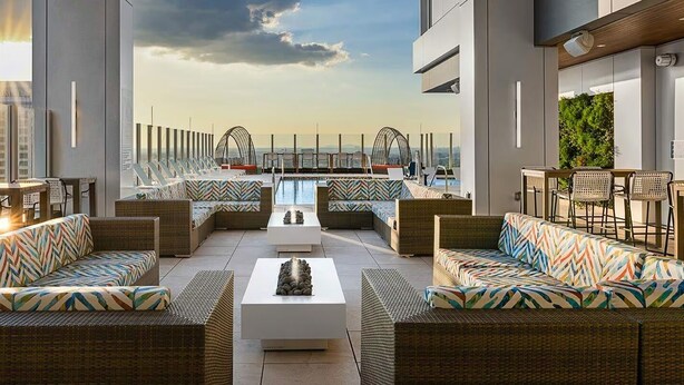 A rooftop lounge with wicker furniture, a pool, and a view of the city skyline. - FIFA Luxury-1BR Presidential Ste-Parking Incl.-Walk to Stadium-Sleeps 4 (Atlanta)