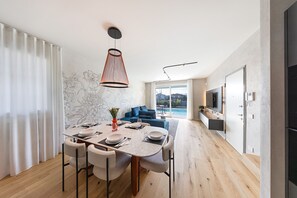 A modern dining area with a large table, chairs, and a hanging light fixture.
