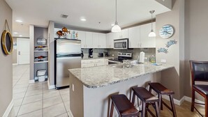 Eine moderne Küche mit Granit-Arbeitsplatten, Edelstahlgeräten und einer zentralen Kochinsel mit Barhocker.