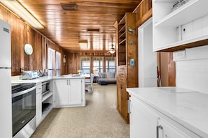 Una cocina con paneles de madera, armarios blancos, un microondas y una estufa.